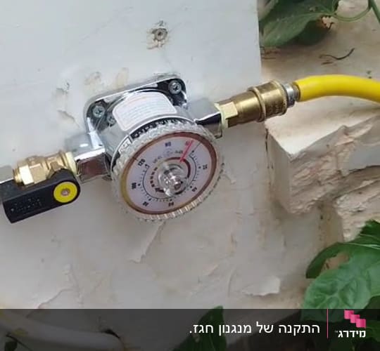 מד לחץ גז מותקן על קיר עם צינור צהוב